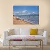 Unknown people collect fish from fishing nets at the beach with fishing boats Multi panel canvas wall art