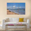 Unknown people collect fish from fishing nets at the beach with fishing boats Multi panel canvas wall art