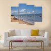 Unknown people collect fish from fishing nets at the beach with fishing boats Multi panel canvas wall art