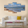 Unknown people collect fish from fishing nets at the beach with fishing boats Multi panel canvas wall art