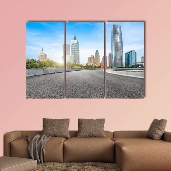 The empty asphalt road is built along modern commercial building wall art