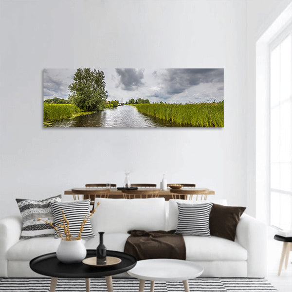 Canal banks with reeds and Typha under cloudy summer sky panoramic canvas wall art