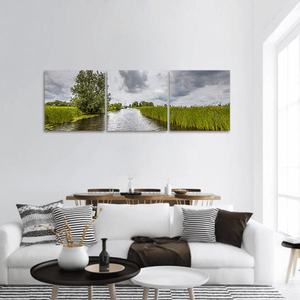 Canal banks with reeds and Typha under cloudy summer sky panoramic canvas wall art