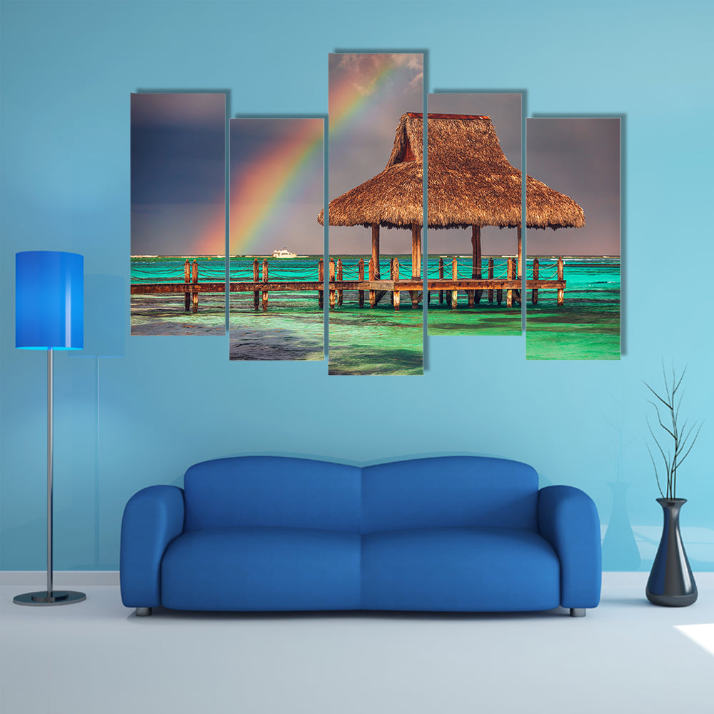 The rainbow over the wooden water villa in Cap Cana, Dominican Republic Multi Panel Canvas Wall Art