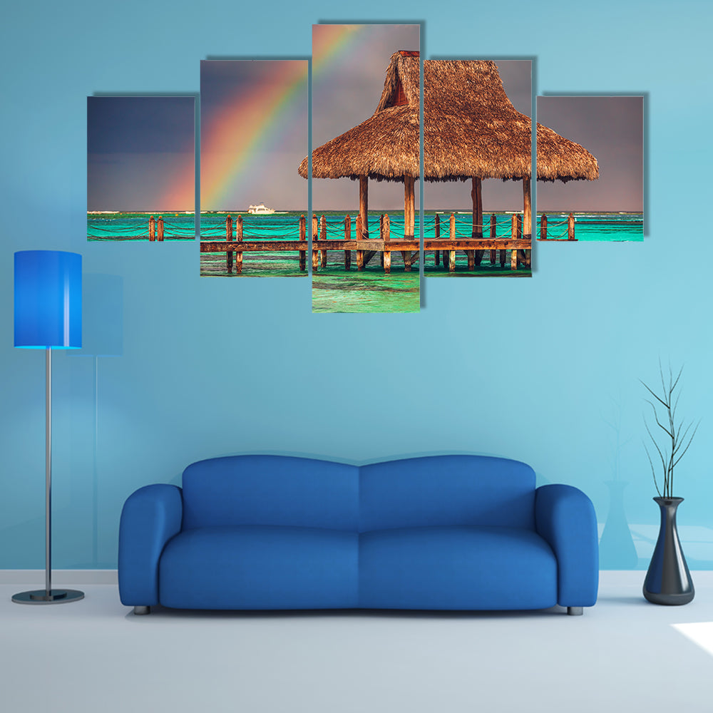 The rainbow over the wooden water villa in Cap Cana, Dominican Republic Multi Panel Canvas Wall Art