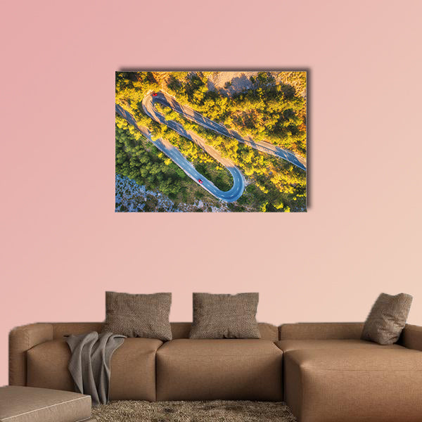 Aerial view of mountain curve road with cars, green forest at sunset wall art