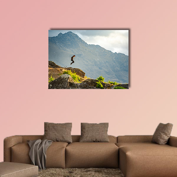Young man jumping on Queenstown hill multi panel canvas wall art