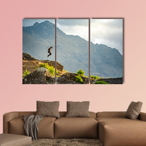 Young man jumping on Queenstown hill multi panel canvas wall art