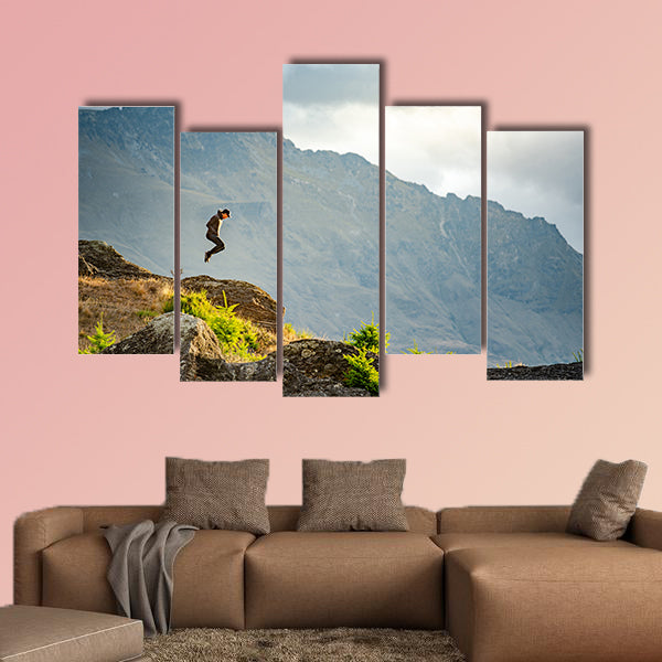 Young man jumping on Queenstown hill multi panel canvas wall art