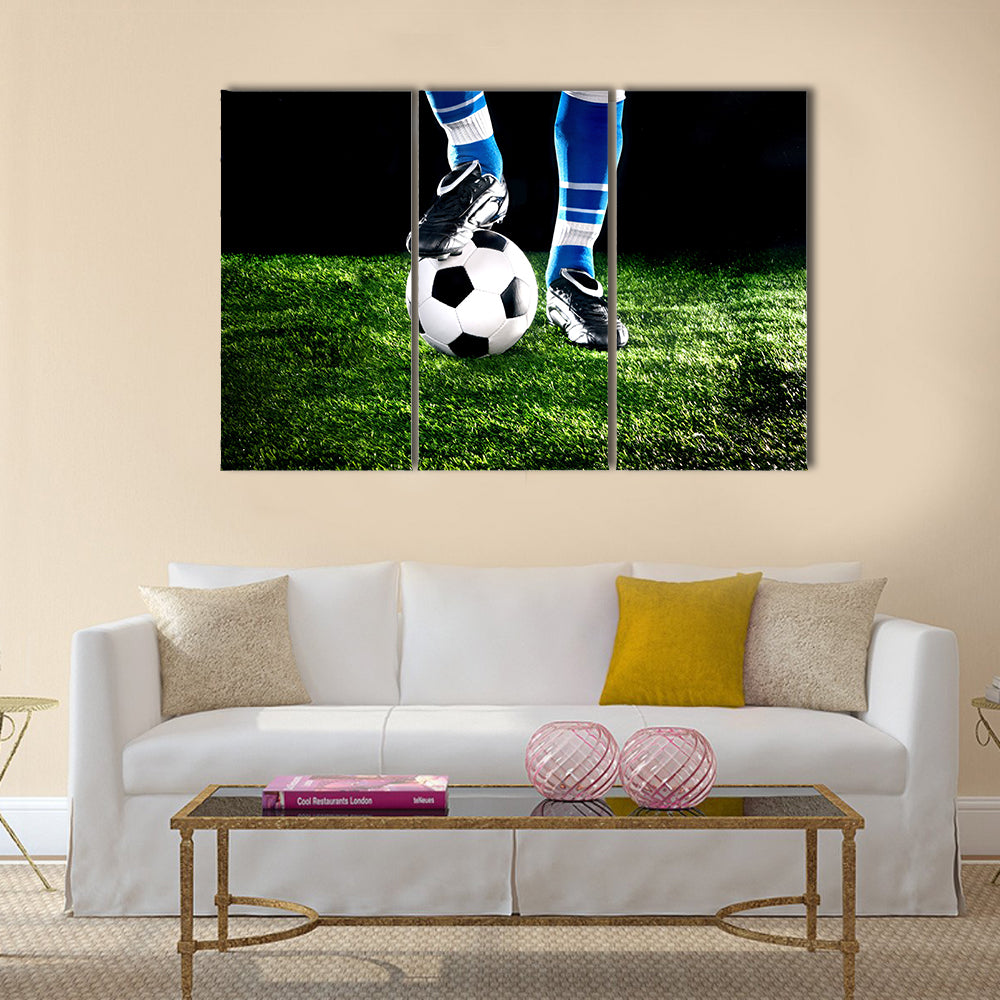 Soccer ball with his feet on the football field Multi panel canvas wall art