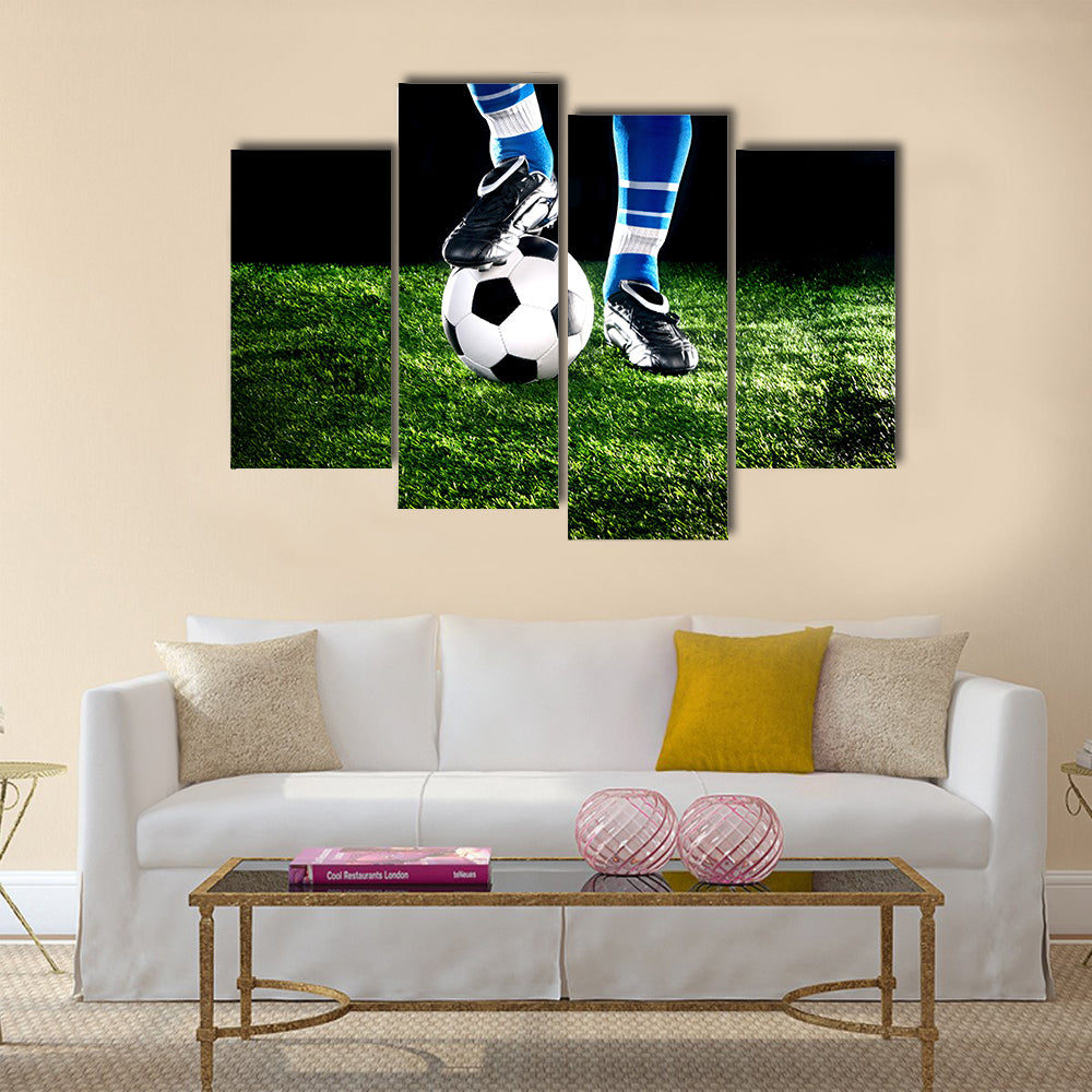 Soccer ball with his feet on the football field Multi panel canvas wall art