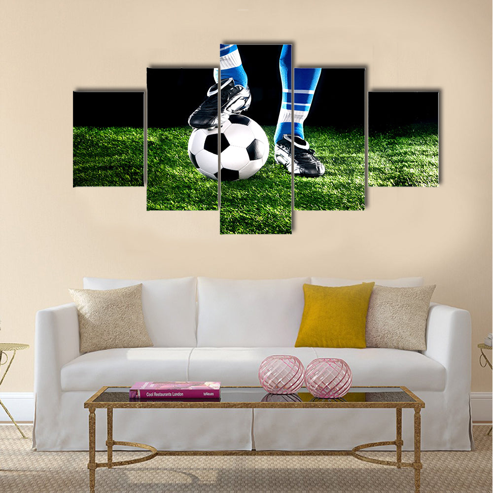 Soccer ball with his feet on the football field Multi panel canvas wall art