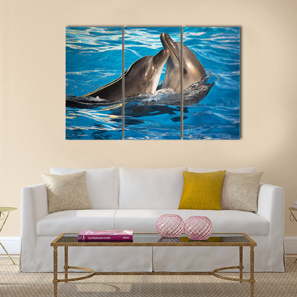 Pair of dolphins dancing in light-blue water Multi Panel Canvas Wall Art
