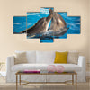 Pair of dolphins dancing in light-blue water Multi Panel Canvas Wall Art