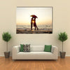 Couple kissing under umbrella at the beach in sunset multi panel canvas wall art