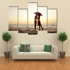 Couple kissing under umbrella at the beach in sunset multi panel canvas wall art