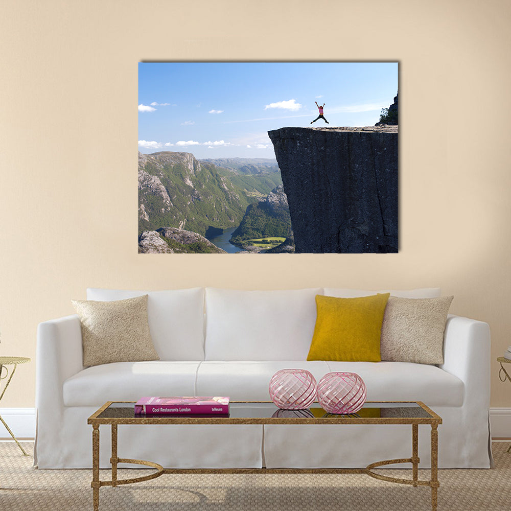 girl hiker jumping on Preikestolen, Preikestolen -famous cliff at the norwegian mountains Multi panel canvas wall art