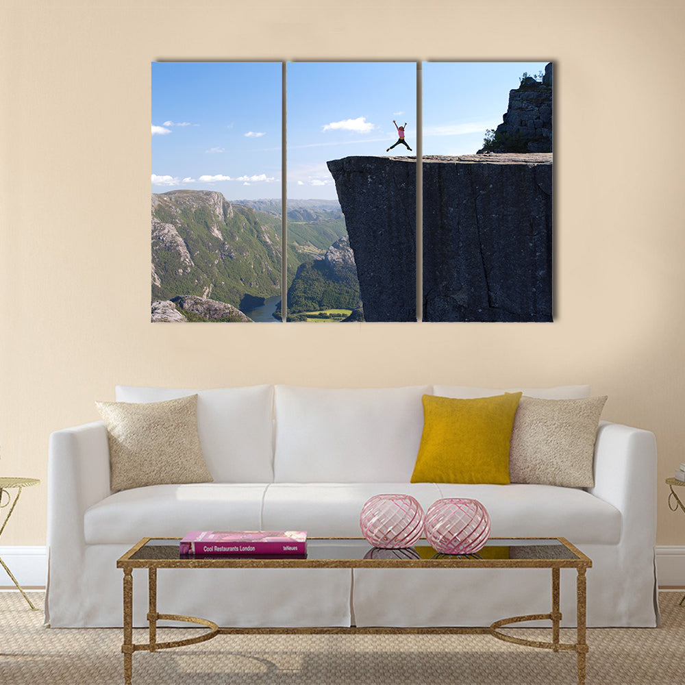 girl hiker jumping on Preikestolen, Preikestolen -famous cliff at the norwegian mountains Multi panel canvas wall art