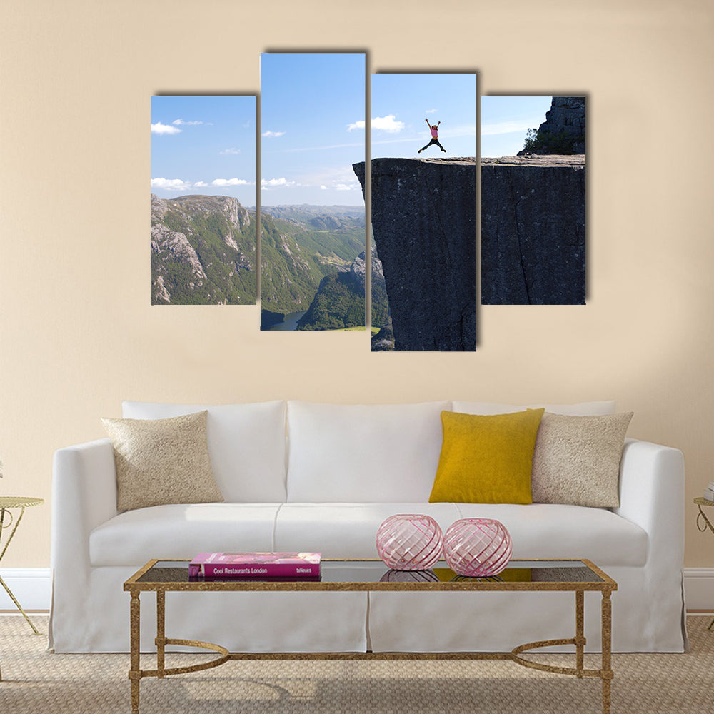 girl hiker jumping on Preikestolen, Preikestolen -famous cliff at the norwegian mountains Multi panel canvas wall art