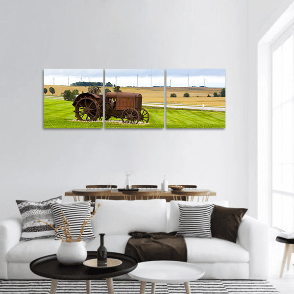 Old rusty tractor with wind turbines in the background panoramic canvas wall art