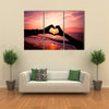 Silhouette hand in heart shape with sunrise in the middle and beach background multi panel canvas wall art