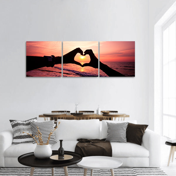 Silhouette hand in heart shape with sunrise and beach panoramic canvas wall art