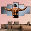 Young bodybuilder showing his biceps on a gray background Multi panel canvas wall art