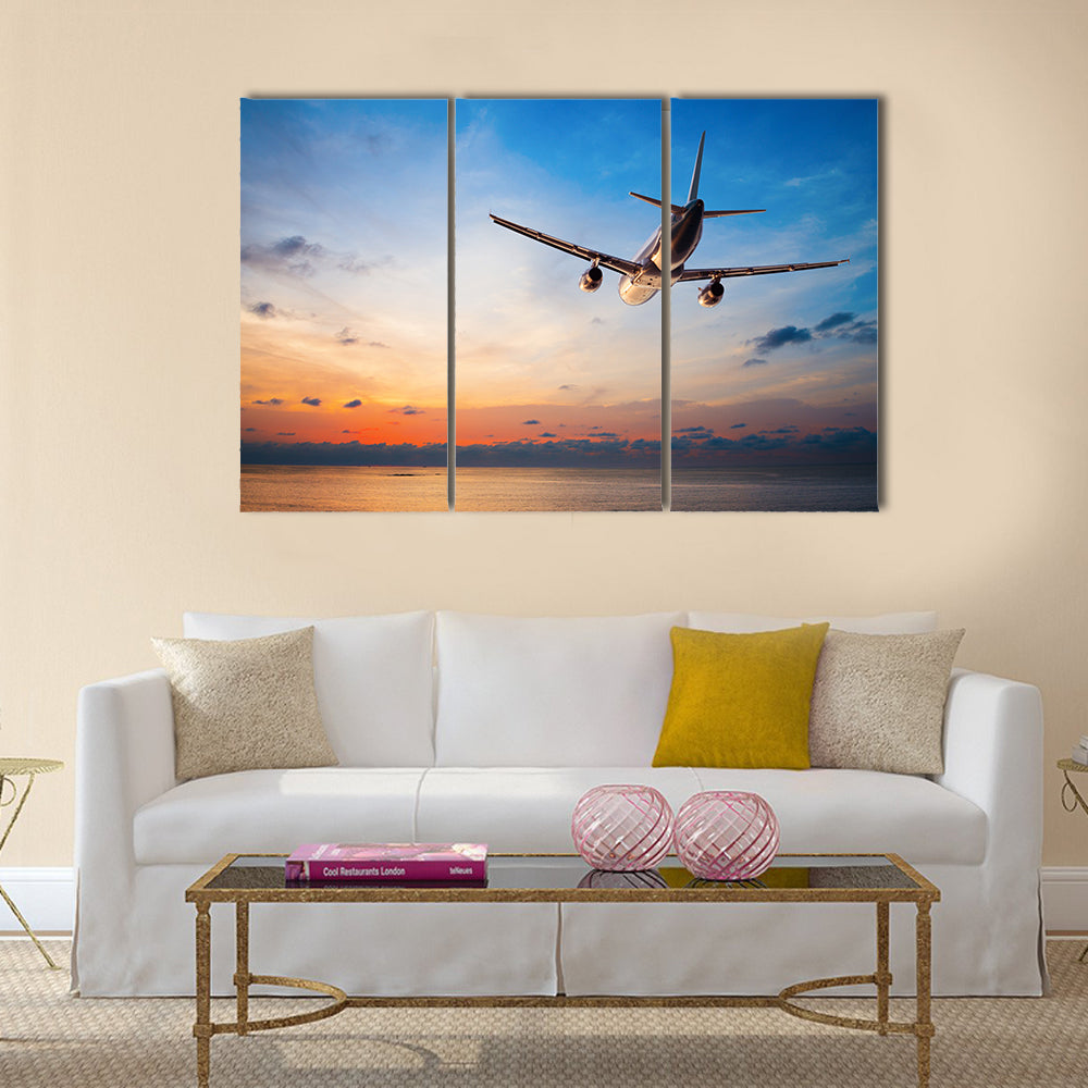 Airplane flying above tropical sea at sunset multi panel canvas wall art