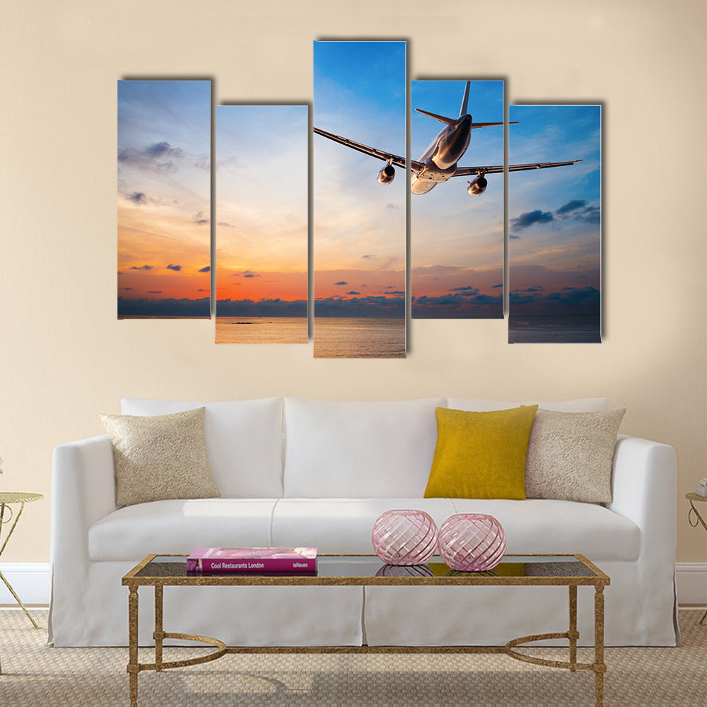 Airplane flying above tropical sea at sunset multi panel canvas wall art