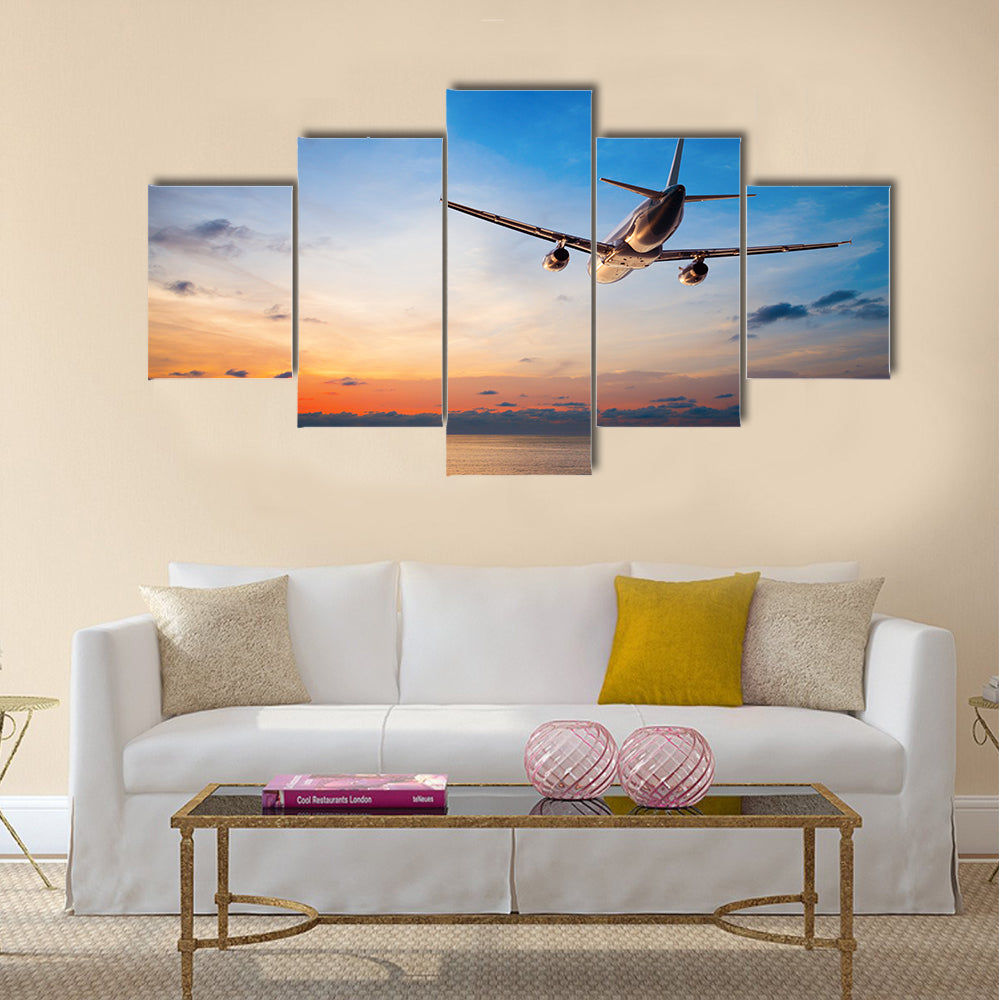 Airplane flying above tropical sea at sunset multi panel canvas wall art