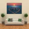 A young couple share a romantic dinner with candles heart on the sea sand beach multi panel canvas wall art