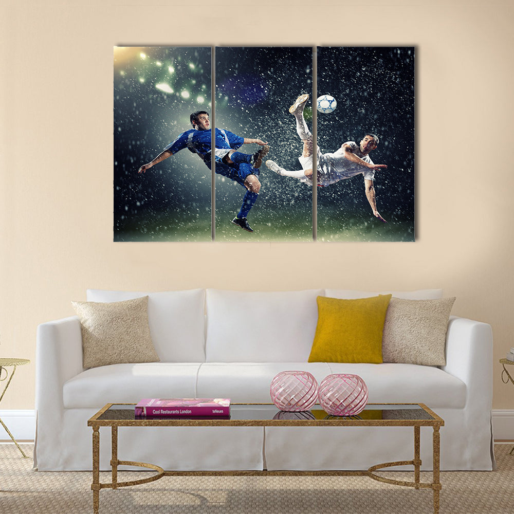 Two football players in jump to strike the ball at the stadium under rain Multi panel canvas wall art