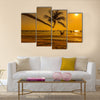 Sunset with palm and longtail boats on tropical beach. multi panel canvas wall art