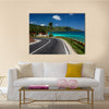 Asphalt road along tropical coastline with palm trees and buildings on a side multi panel canvas wall art