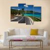 Asphalt road along tropical coastline with palm trees and buildings on a side multi panel canvas wall art