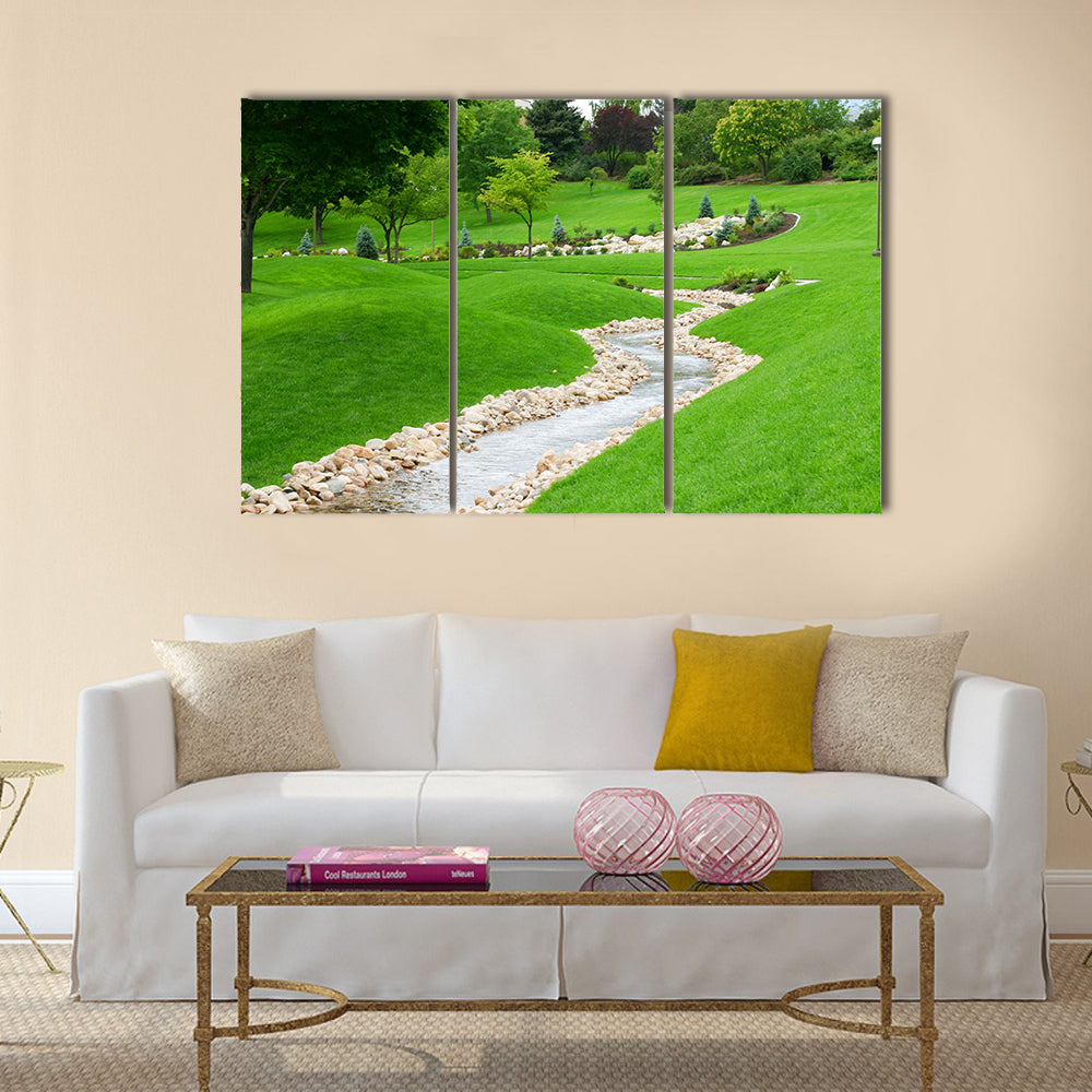 Stream of water flowing through grassy hills with trees Multi Panel Canvas Wall Art
