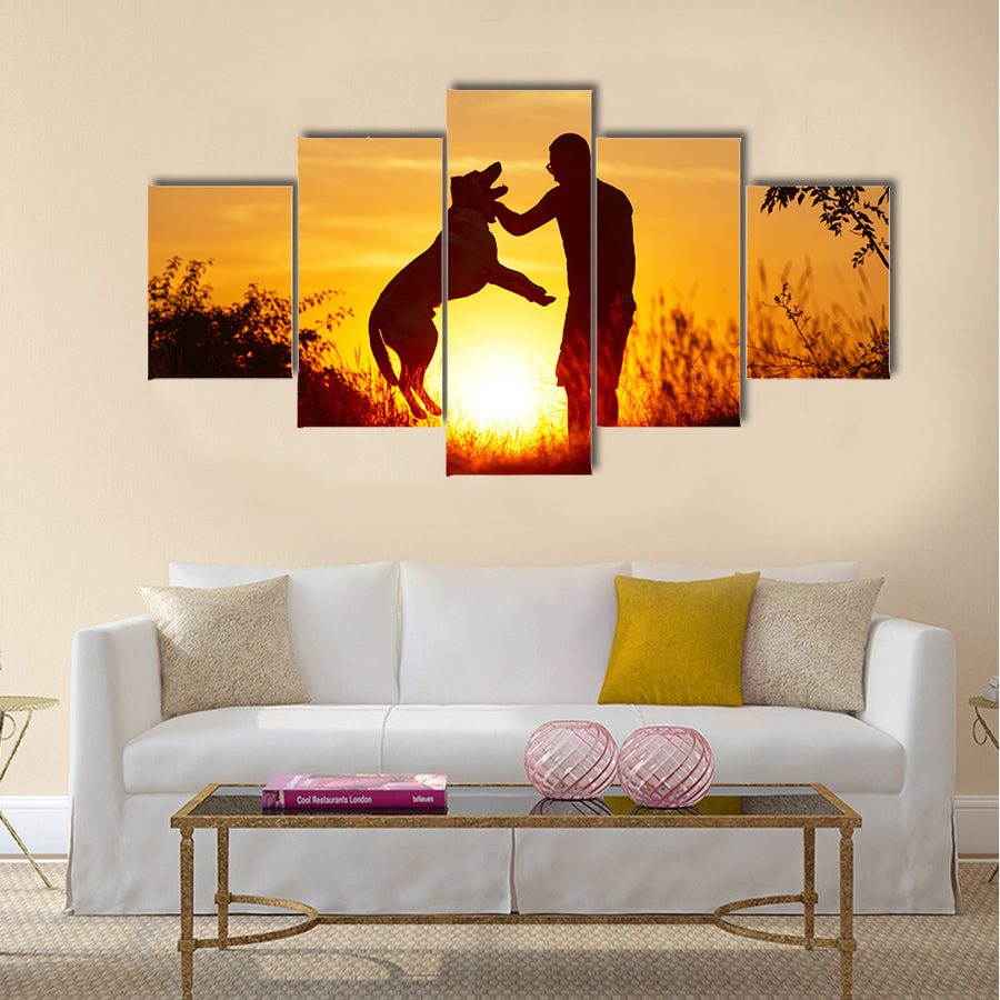 Young man with his yellow labrador retriever in nature - back lit  Multi panel canvas wall art