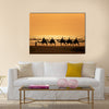 Tourists ride camels train on the sea at sunset, Morocco Multi panel canvas wall art