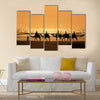 Tourists ride camels train on the sea at sunset, Morocco Multi panel canvas wall art