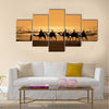 Tourists ride camels train on the sea at sunset, Morocco Multi panel canvas wall art