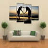 Two girls make heart with sea and sun down background multi panel canvas wall art