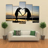 Two girls make heart with sea and sun down background multi panel canvas wall art