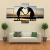 Two girls make heart with sea and sun down background multi panel canvas wall art