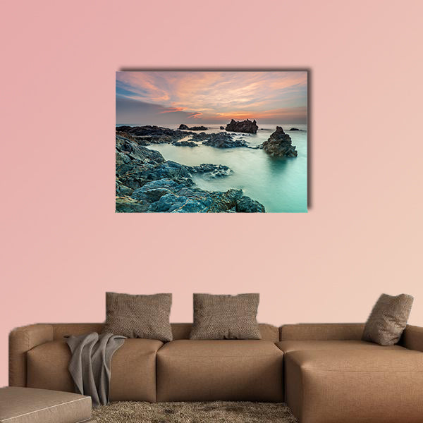 Coloring sky during sunrise with rocks on the beach wall art
