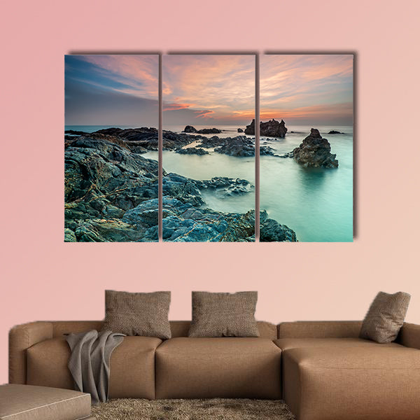 Coloring sky during sunrise with rocks on the beach wall art