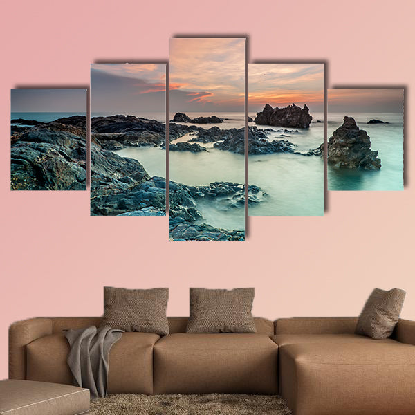 Coloring sky during sunrise with rocks on the beach wall art