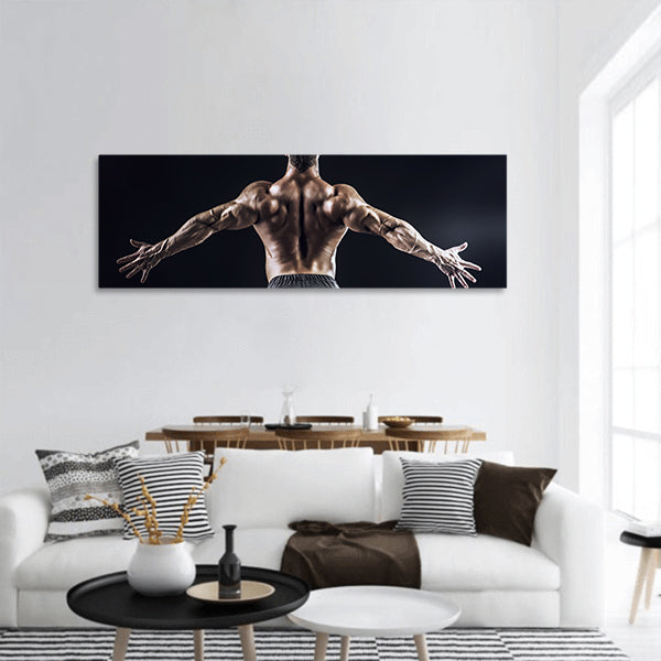 Muscular man bodybuilder posing back over dark Panoramic Canvas Wall Art