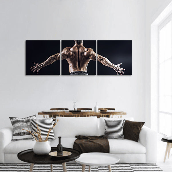 Muscular man bodybuilder posing back over dark Panoramic Canvas Wall Art