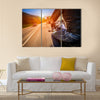 Biker driving a motorcycle rides along the asphalt road Multi panel canvas wall art