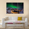 A man looking at the Northern lights over Reine, Lofoten islands, Norway Multi panel canvas wall art